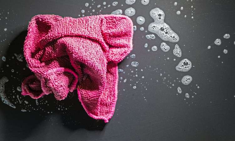 Pink washcloth on the black background with soap foam